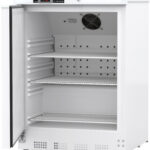 A white Undercounter Controlled Room Temperature Cabinet with a transparent door open to the left reveals three adjustable metal shelves inside. The control panel displays the temperature at the top right, and a ventilation fan is mounted on the back wall.
