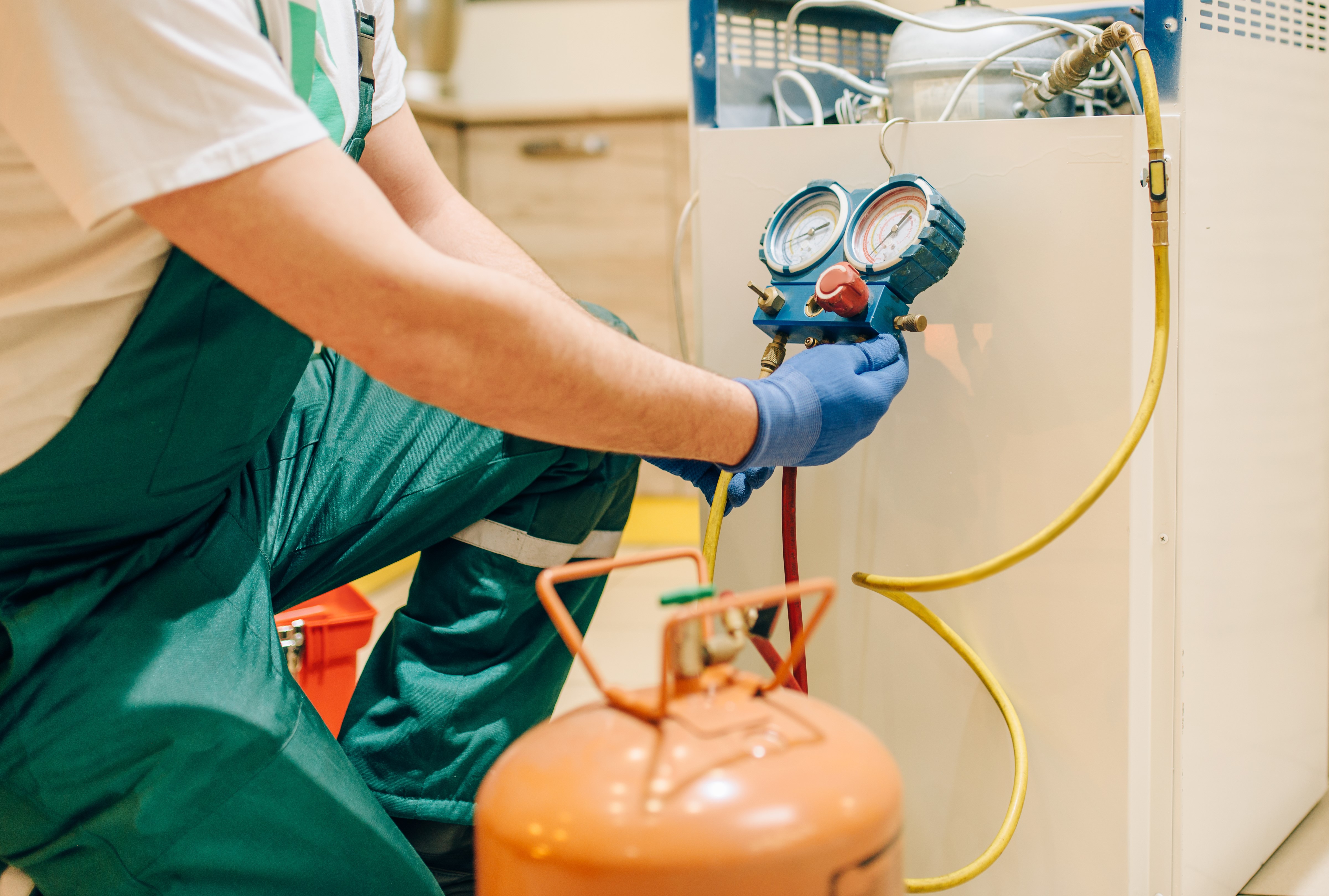 worker-fills-refrigerator-compressor