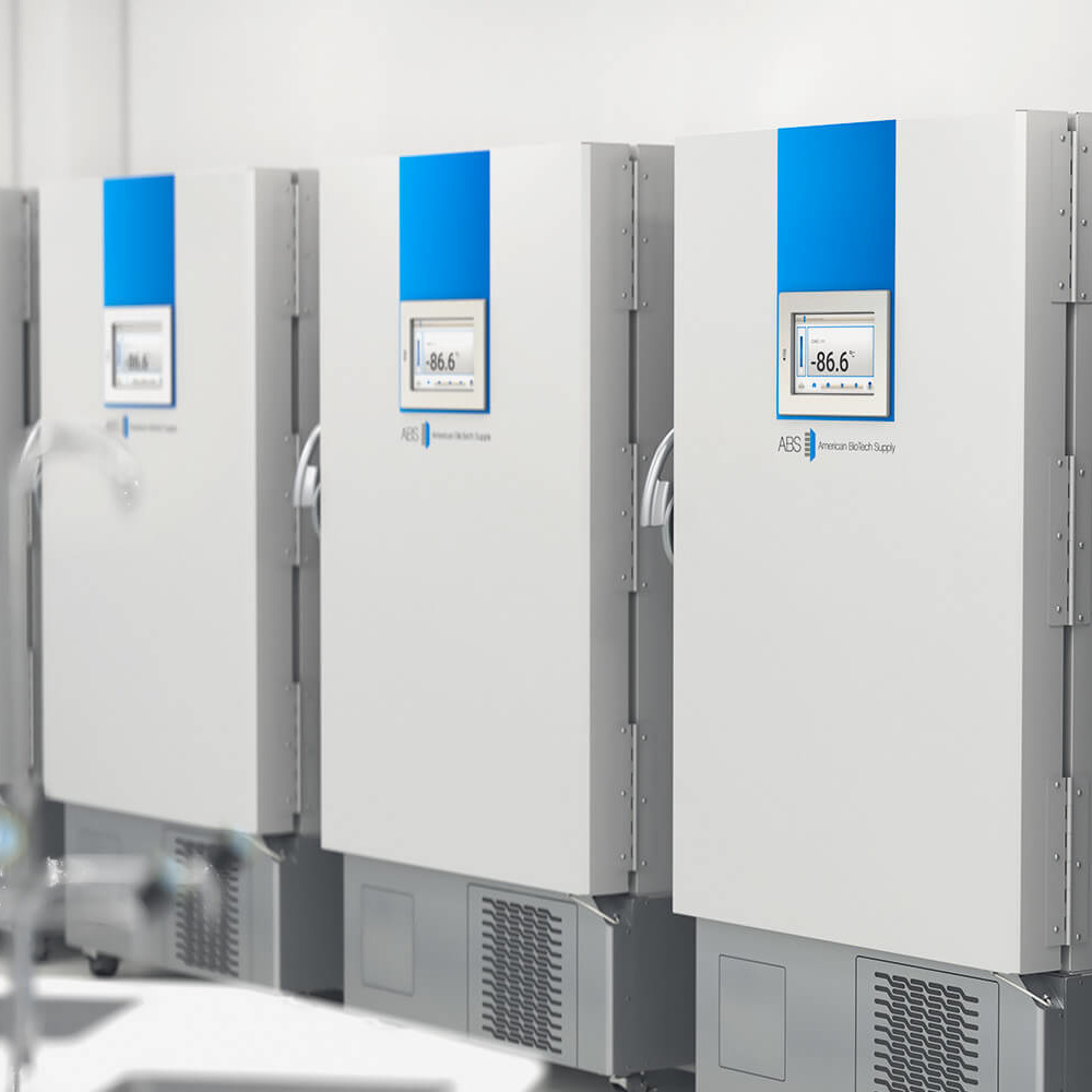 Three large white laboratory freezers with digital temperature displays showing -86.6°C are lined up against a wall in a clean, bright room. The freezers have blue accents and vents at the bottom. The environment appears sterile and modern.