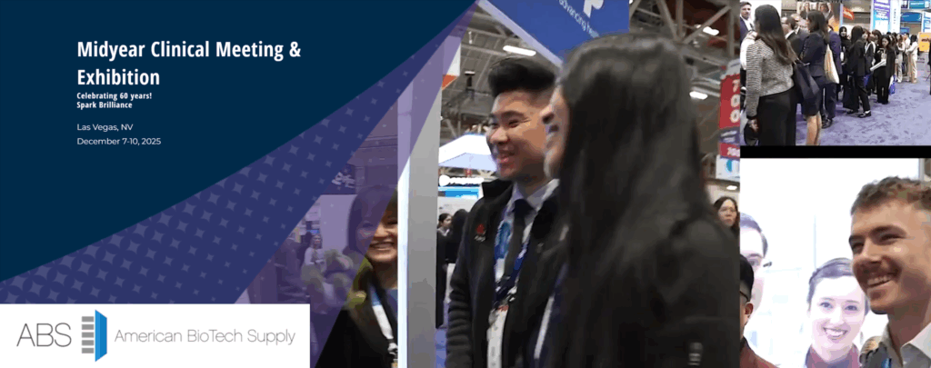 A group of smiling people in business attire stand at an exhibition booth. The screen displays Midyear Clinical Meeting Exhibition, event details, and the American BioTech Supply logo, with a busy expo floor and other attendees in the background.