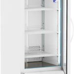 A white, upright laboratory refrigerator with a glass door is shown open. It has three adjustable wire shelves inside, a digital temperature display above the door, and is mounted on four caster wheels for mobility. The interior is brightly lit.