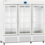 A large, white, three-door commercial refrigerator with glass doors and metal handles. Each section has multiple adjustable wire shelves. The unit has vents along the bottom and a digital temperature display above the middle door. The refrigerator is on wheels.