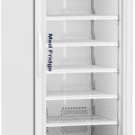 A tall, white medical refrigerator with a glass door showing seven empty shelves inside. The display panel at the top shows a digital temperature reading. The fridge is labeled “Med Fridge” on the side and stands on wheels.