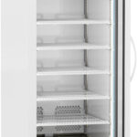 A tall, white laboratory refrigerator with a glass door, digital temperature display, and multiple empty wire shelves. The door is open, revealing the interior and shelves. The unit has wheels and ventilation grilles at the bottom.