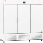 A large, white, three-door commercial refrigerator on wheels with a digital control panel and ventilation grilles along the bottom. The surface is clean, with simple handles on each door and a small green sticker on the lower right corner.