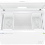 A white chest freezer with the lid open, showing two removable white baskets inside. The freezer’s interior is empty, and logos for ABS and another green circular symbol are visible on the front panel. The freezer is clean and well-lit.