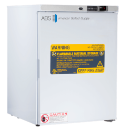 A white American BioTech Supply ABS laboratory refrigerator with a digital display, large yellow “Flammable Material Storage” warning label, safety instructions, caution symbols, and a smaller red “Caution” label on the front door.