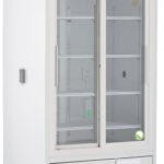 A tall, white, commercial refrigerator with double glass doors, metal frame, and visible shelves inside. It has a digital temperature display on the top, vents at the bottom, and is mounted on four wheels for mobility.