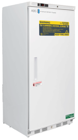 A tall, white laboratory refrigerator by American BioTech Supply stands upright. The door has warning labels, including a yellow sign reading “Flammable Material Storage” and “Keep Fire Away.” A handle is centered vertically on the door’s left edge.
