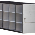 A metal airline catering box with a black frame, open on one side showing four vertical compartments, each divided into two horizontal sections, totaling eight storage spaces; a hinged door with a metal handle is open to the right.