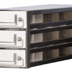 A metallic storage unit with three pull-out drawers, each featuring a rectangular metal handle. The drawers are stacked vertically within a rectangular frame, and the unit appears industrial and sturdy, suitable for organizing small tools or parts.