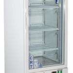 A tall, white laboratory refrigerator with a glass door, metal shelves, digital display, and control buttons at the bottom, standing on four wheels. The label American BioTech Supply is visible on the top front panel.
