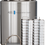 A large stainless steel liquid nitrogen storage tank labeled “ABS American BioTech Supply” stands upright. In front are two tall metal racks for holding samples and a flexible insulated hose. The tank features a digital display and blue lid on top.