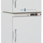 A white medical freezer sits on top of a matching medical fridge. Both have digital displays, ABS American BioTech Supply branding, and vertical blue labels reading “Med Freezer” top and “Med Fridge” bottom. The fridge shows eco-friendly stickers.